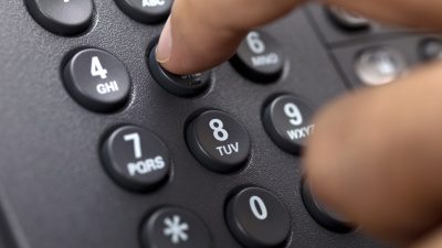 En människas fingrar trycker ner knappar på en telefon
