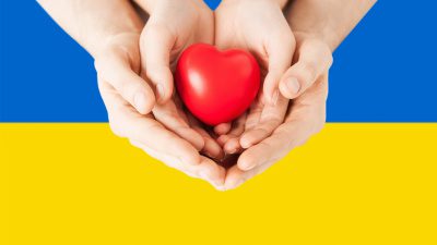 ukrainska flaggan som bakgrund till två händer som håller ett hjärta.
