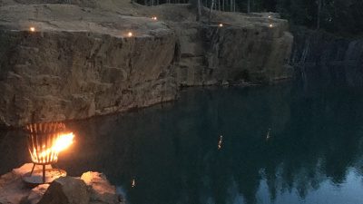 Naturbild över östra Silvbergs gruva i skymningen, Eldar brinner vid vattnet