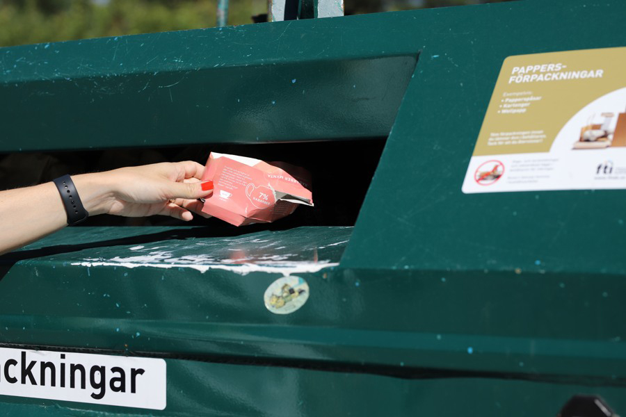 En person slänger en pappersförpackning till återvinning.