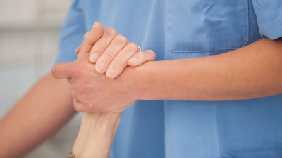 En sjuksköterska håller en patient i handen